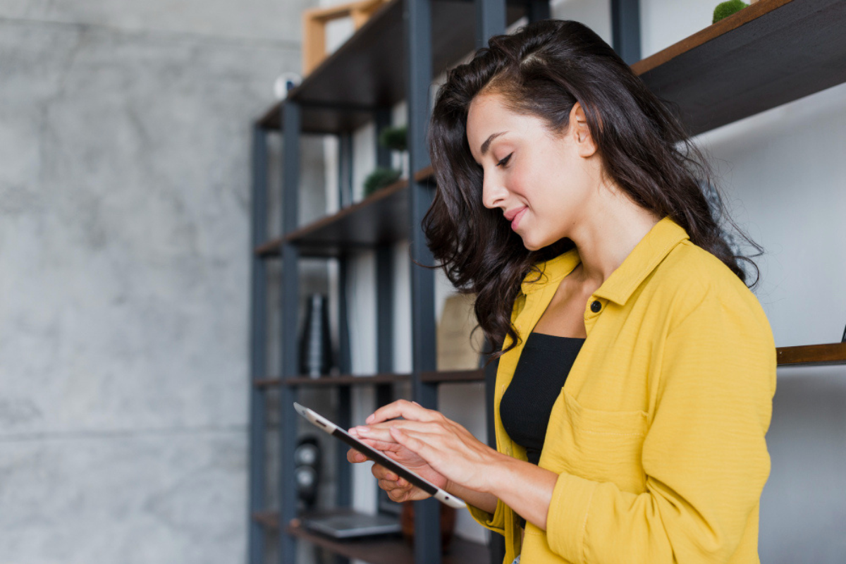 Mulher em pé em ambiente de escritório usando tablet representando: Qual o objetivo da Reforma Tributária?