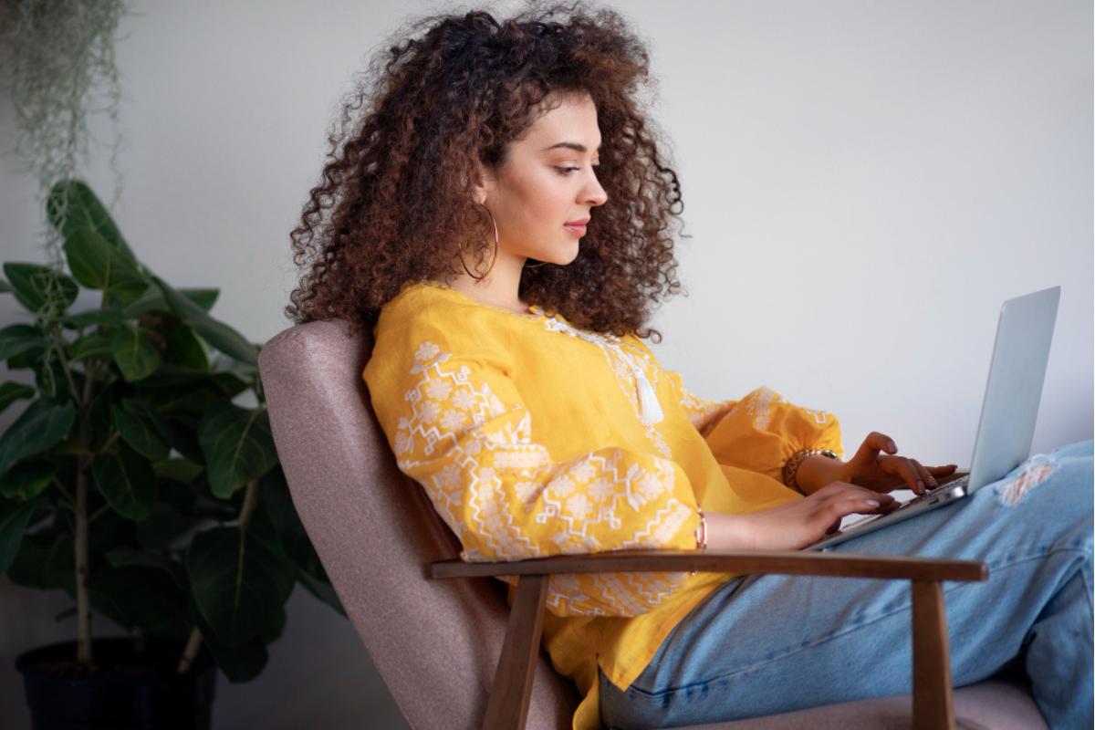 Mulher sentada em poltrona confortável com usando notebook no colo em ambiente de home office representando: Duplicidade de notas fiscais: como identificar, corrigir e evitar autuações.