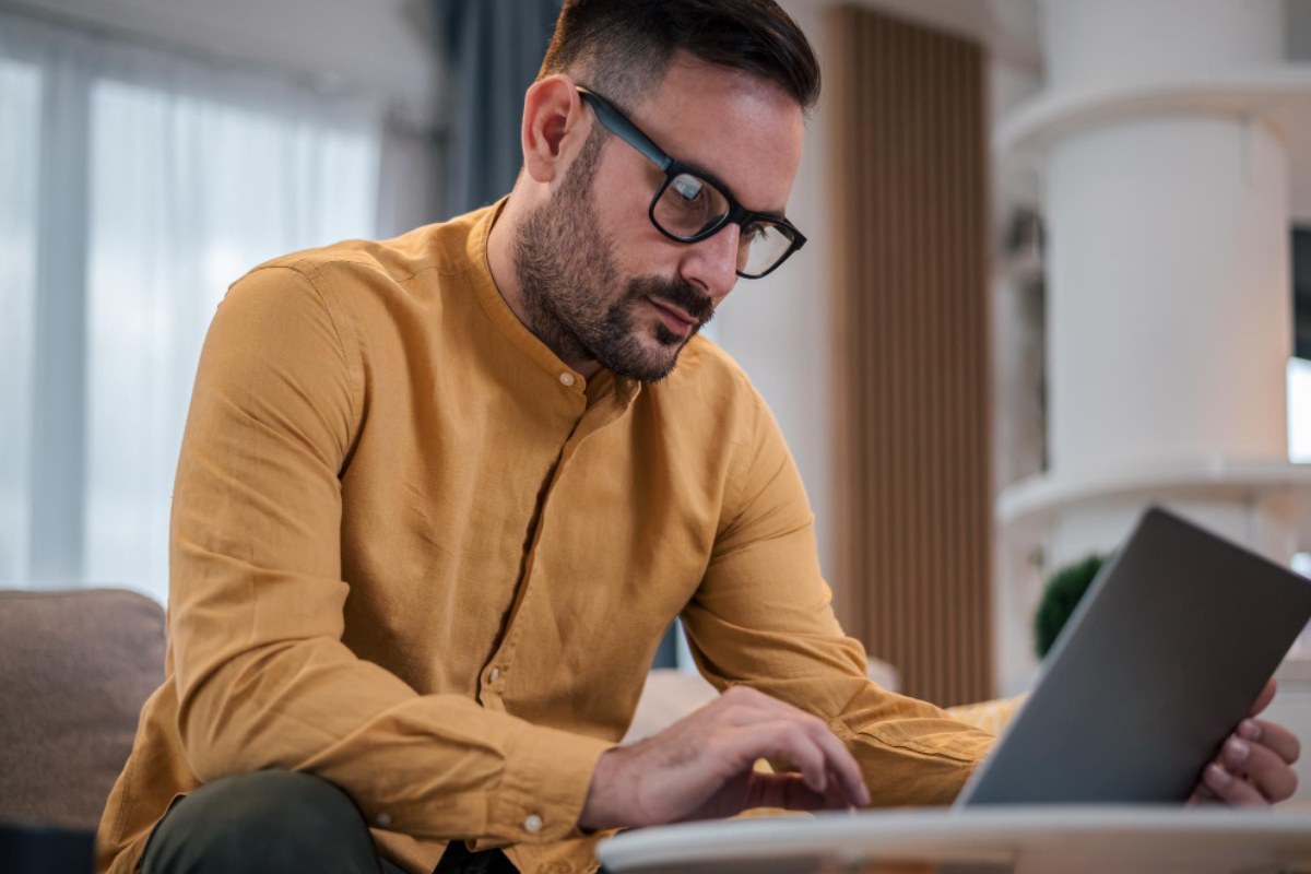 Homem sentado trabalhando em um notebook em ambiente home office representando: Rejeição 225: como corrigir a falha no Schema XML da NF-e.