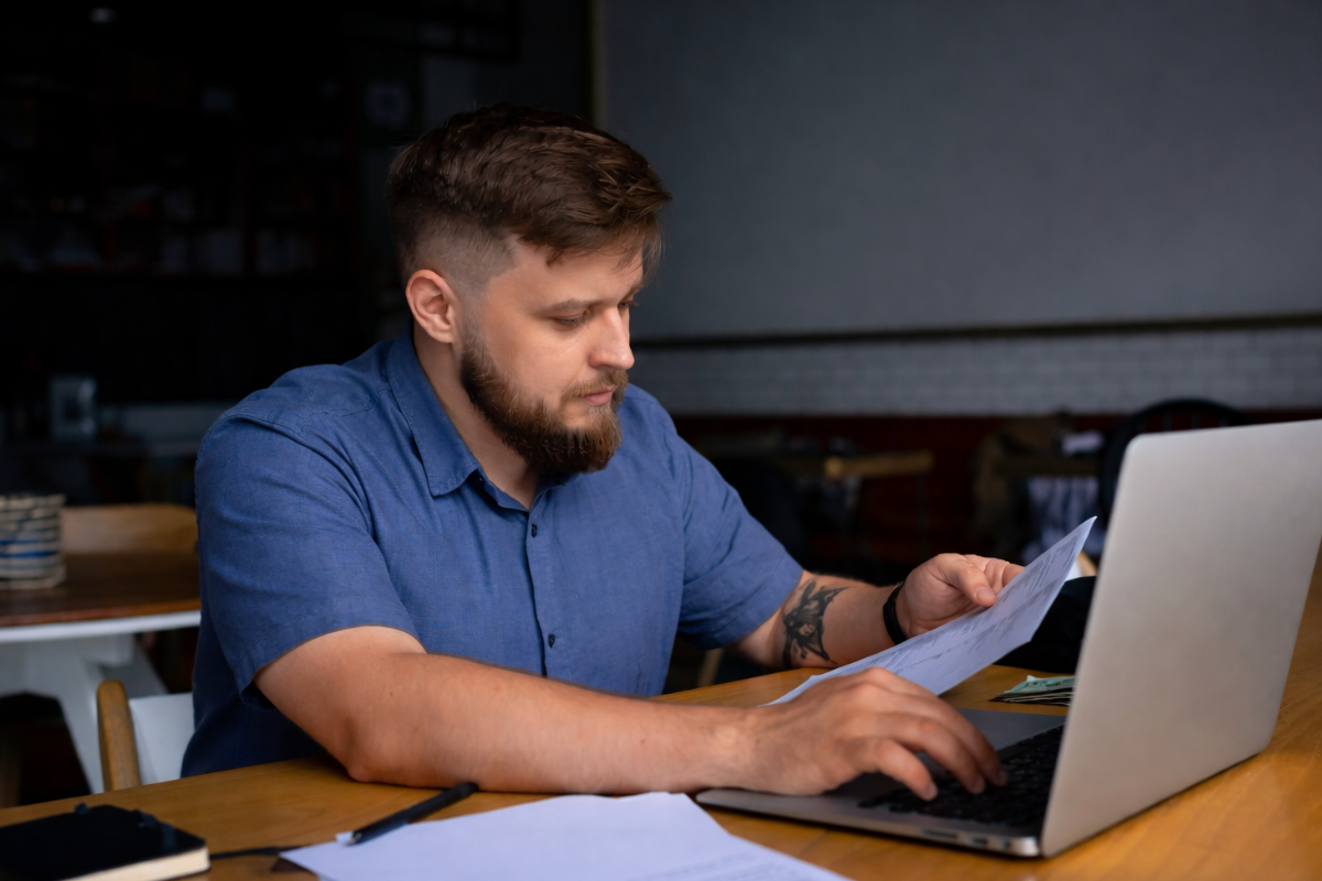 Homem sentado trabalhando em um notebook em ambiente home office representando: Como funcionará a autuação fiscal durante a Reforma Tributária?