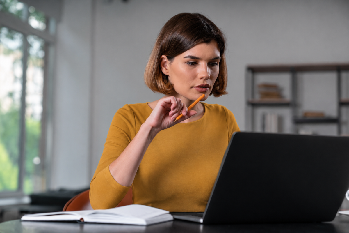 Mulher trabalhando em um notebook sobre uma mesa em ambiente de escritório representando: Como erros de CFOP afetam o financeiro da empresa.