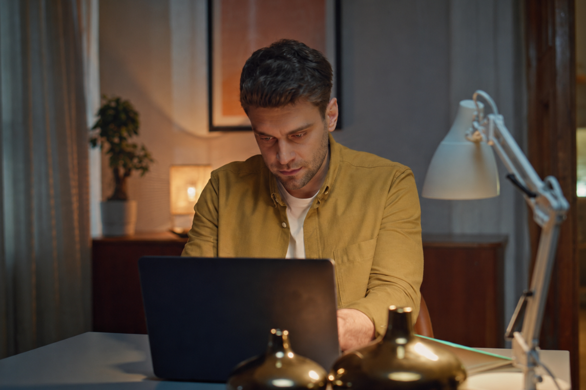 Homem sentado trabalhando em um notebook em ambiente home office representando: Quais são os campos obrigatórios no XML com IBS e CBS?