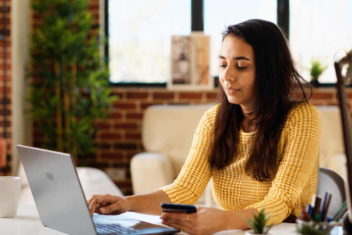 Mulher trabalhando sentada em um notebook sobre uma mesa de escritório representando: Diferença entre erro operacional e infração tributária.